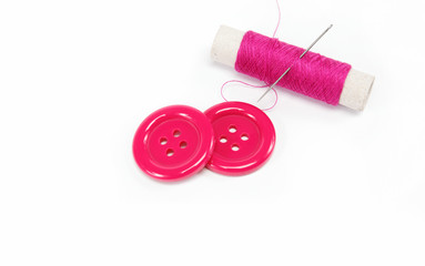 Reel of thread with a needle and buttons on a white background.