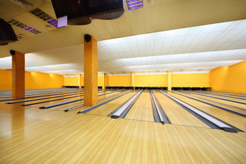 Empty light bowling club, lot of bowling lanes, yellow walls