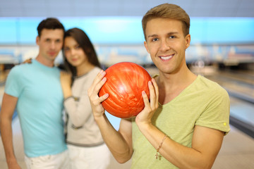 Fototapeta na wymiar Smiling man holds orange ball; pair stands behind him