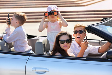 Happy father, mother and two children ride in convertible car