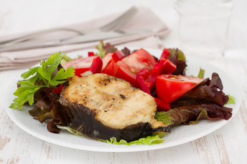 grilled fish with salad on the white plate