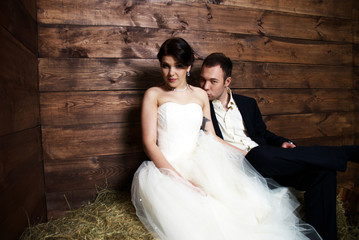 couple in their wedding clothes in barn with hay