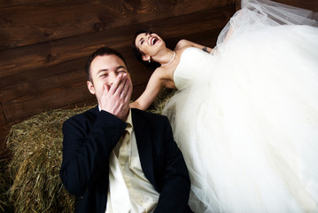 couple in their wedding clothes in barn laughing
