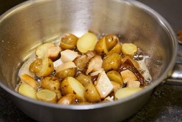 Potatos and mushrooms being fried in pan