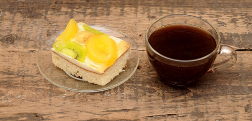 Close-up of glass cup of coffee and apricot cake on wooden table