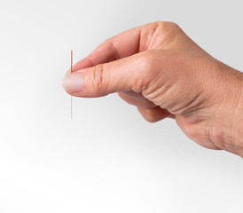 Hand hält Akupunkturnadel