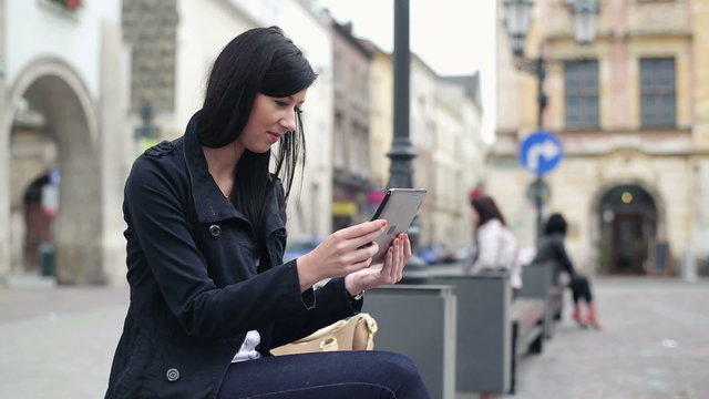 Happy young woman with tablet computer in the city