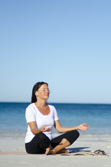 Fototapeta na wymiar Pretty woman exercising and meditating at beach