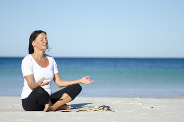Fototapeta na wymiar Mature woman meditating at beach