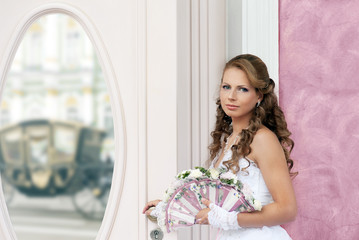 Bride with wedding fan-bouquet near the mirror