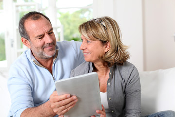 Senior couple looking at web pages on electronic tablet