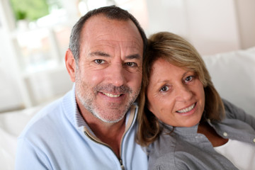 Portrait of happy senior couple sitting in sofa
