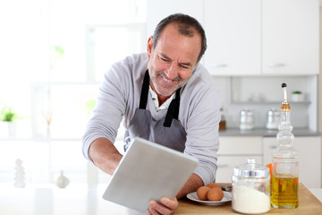 Senior man in kitchen using electronic tablet