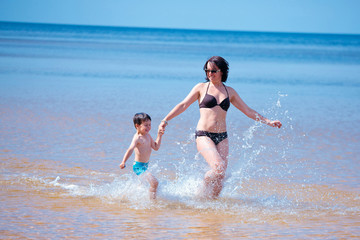 Happy mother and her little son at the beach