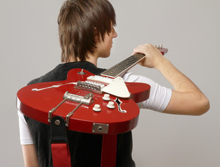 A young boy standing with his back with bass guitar