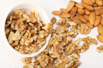 Almonds and walnuts spilled out of white bowl