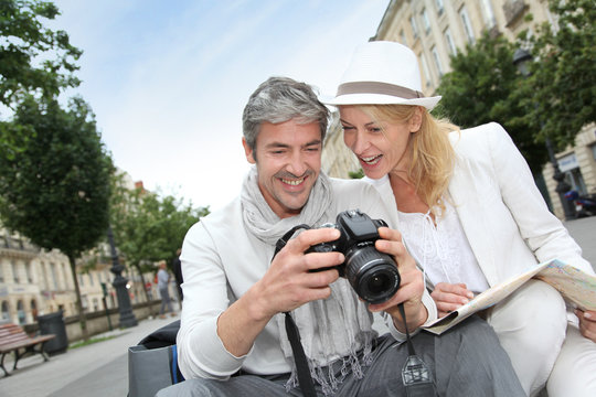 Happy tourists looking at pictures on camera screen