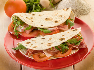 piadina with ham arugula and tomatoes, typical italian sandwich