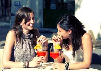 two happy girls while they drink a cocktail