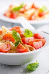 Pasta salad with cherry tomatoes and basil leaves