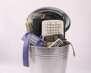 different computer parts and phone in trash can
