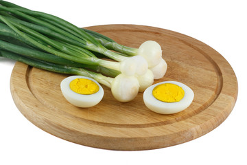Green onions and half of the eggs on a wooden kitchen board