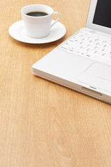 テーブルの上のノートパソコンとコーヒーカップ