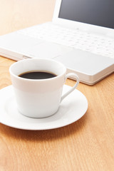 Fototapeta na wymiar Laptop i filiżankę kawy na stole