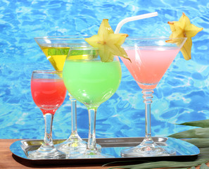 Glasses of cocktails on wooden table on blue sea background