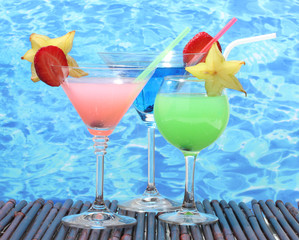 Glasses of cocktails on table on blue sea background