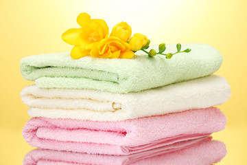 Obraz na płótnie Canvas colorful towels and flowers on yellow background