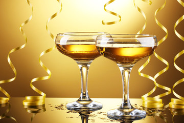 glasses of champagne and streamer on yellow background