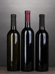 Bottles of great wine on wooden table on grey background