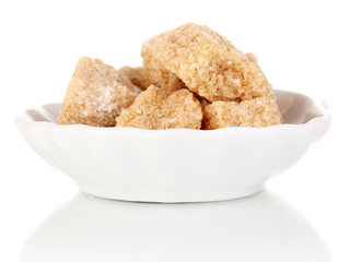 Lump brown cane sugar cubes on saucer isolated on white