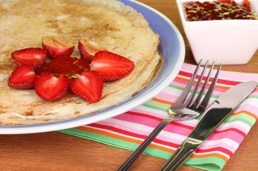 Stack of tasty pancakes on wooden table on green background
