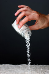 Womans hand holding the salt shaker on grey background close-up