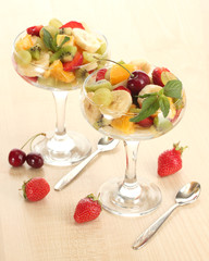 Fresh fruits salad and strawberries on wooden table