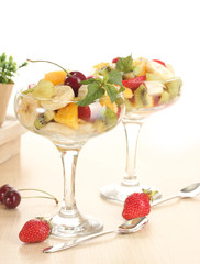 Fresh fruits salad and strawberries on wooden table