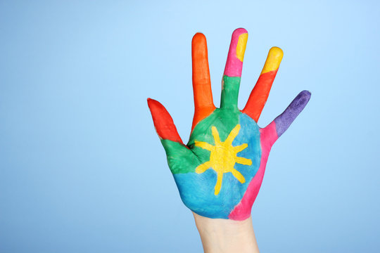 Brightly colored hand on blue  background close-up