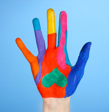 Brightly colored hand on blue  background close-up