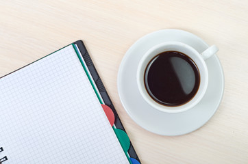 Fototapeta na wymiar Coffee cup with note book on table