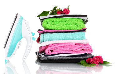 Pile of colorful clothes and electric iron with roses isolated
