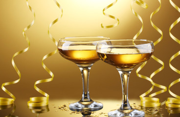 glasses of champagne and streamer on yellow background