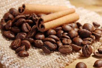 coffee beans and cinnamon sticks on sacking on wooden table