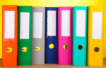 bright office folders on wooden table on yellow background