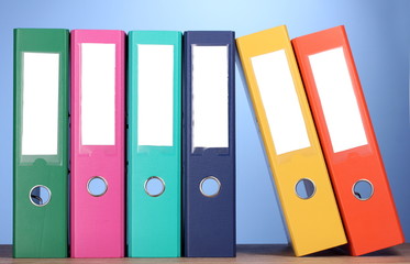 bright office folders on wooden table on blue background