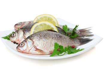 Fresh fishes with lemon and parsley on plate isolated on white