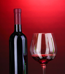 Bottle of great wine and wineglass on red background