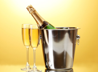 Champagne bottle in bucket with ice and glasses of champagne,