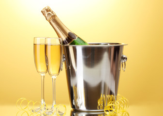 Champagne bottle in bucket with ice and glasses of champagne,